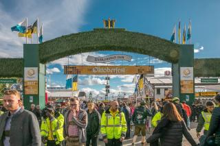 Eingangsbereich zum Oktoberfest in München mit Torbogen, Security und Gästen