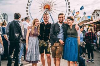 Gruppe von Wiesnbesuchern in Tracht vor dem Riesenrad auf dem Oktoberfest Gruppe von Wiesnbesuchern in Tracht vor dem Riesenrad auf dem Oktoberfest