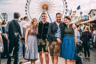 Gruppe von Wiesnbesuchern in Tracht vor dem Riesenrad auf dem Oktoberfest