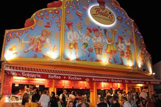 Bodo’s Cafézelt & Cocktailbar vereint seit nun mehr über 30 Jahren hausgemachte Konditoreispezialitäten mit bestem Service von den hübschesten Wiesn-Bedienungen und ausgelassener Partystimmung