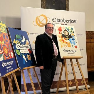 Referent Clemens Baumgärtner neben dem Gewinner-Plakat und den 2 weiteren Finalisten-Motiven
